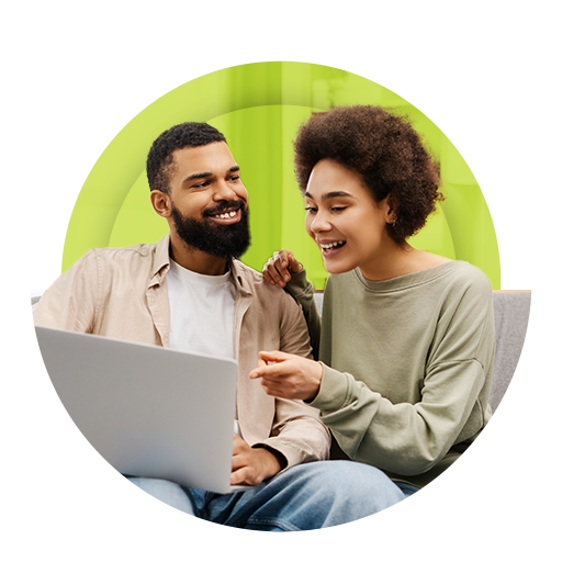 Casal jovem juntos, mulher apontando para o  notebook e sorrindo.