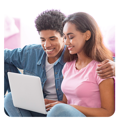 Casal de jovens negros, os dois sorrindo, olhando o notebook no colo dela.